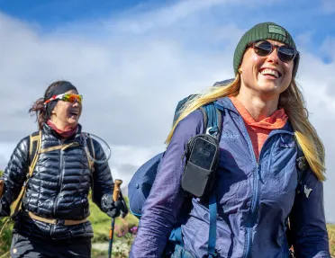 Two women smiling while hikings in an open field