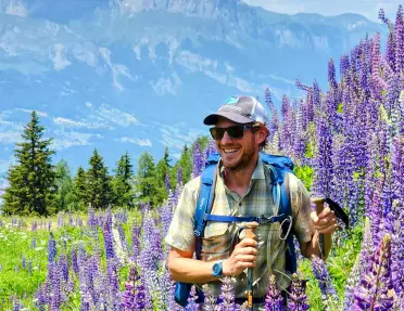 Man hiking with tall lavender flowers to the right