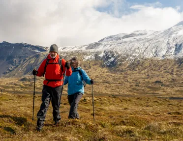 Man and woman with hiking poles, walking in an open valley