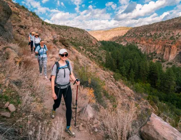 Group of women with walking poles descending a dirt trail