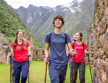 Group of men and women with walking poles, walking through stone ruins