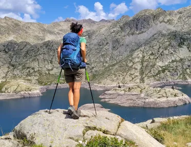 A hiker stops at a lake to look at the view