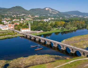 Long stone bridge with a river underneath, leading to a small town