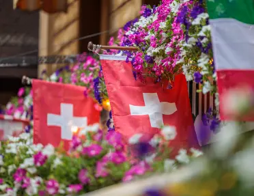 swiss flags hanging from a balcony with flowers