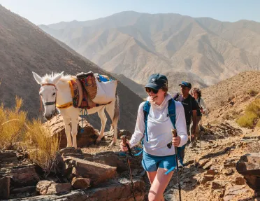 Group of people smiling while hiking next to a white horse