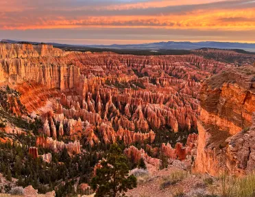 Sky view of a valley of orange canyons with the sunset in the distance