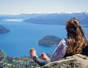 Woman sitting on a cliff, looking down towards the ocean