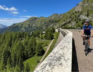 Man biking on a road, looking over a ledge towards a valley