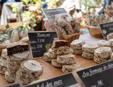 A vibrant display of artisanal French cheeses and charcuterie at a market stall, in Provence or along the French Riviera.
