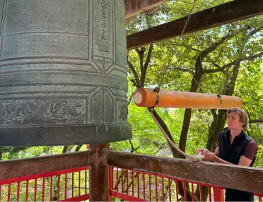 Man looking at a large bell in a temple