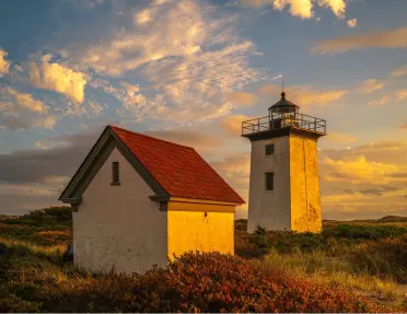 Lighthouse in the middle of a valley with the sunset in the distance