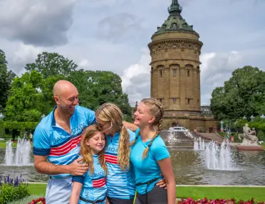 A family posing in front of the historic Mannheim Water Tower on Friedrichsplatz in Germany.