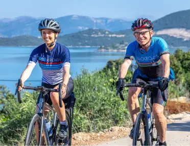 Man and woman biking on a road, with the ocean in the background