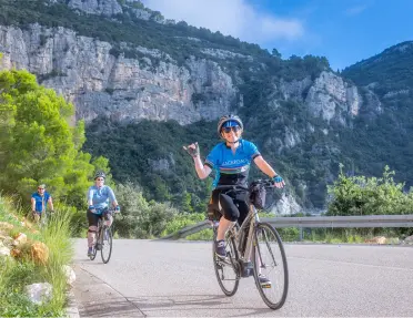 Group of people biking on a road with large mountains and cliffs in the background
