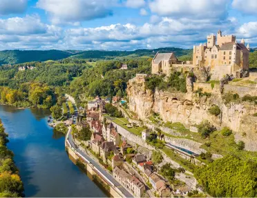 Castle-like building on top of a hill, with a river on the ground floor