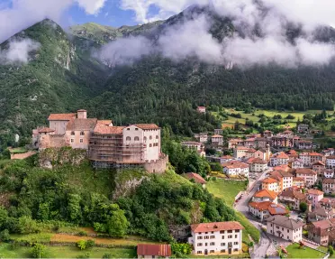 Tall mountains covered in fog, with a small town on the ground level