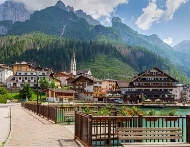 A small town, with tall mountains and trees in the background