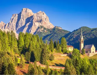 Sunshine hitting tall trees and a church building in a valley