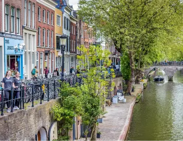 Canal with boats riding through, with a row of hotel buildings to the left