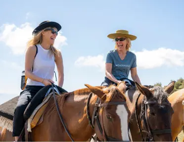 Two women smiling while horseback riding
