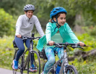 Mom and daughter biking on an empty road, smiling