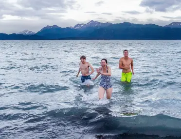 A family plays in the cold coastal waters of Alaska.