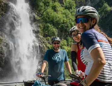 A group of cyclists pose near a waterfall.
