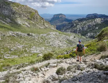 Person walking on a gravel trail in the middle of a valley