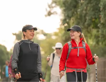 Group of women, using hiking poles and walking through a trail
