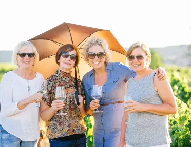4 women wine tasting and holding an umbrella in Spain.