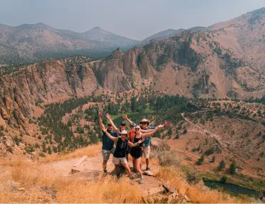 Guests with their arms raised, enjoying a hike in Oregon’s rugged high desert wonderland