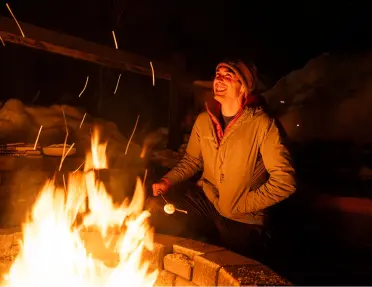 Person smiling while roasting marshmallows on a campfire