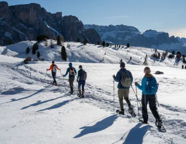 Group of hikers walking through a snowy valley with tall mountains in the distance