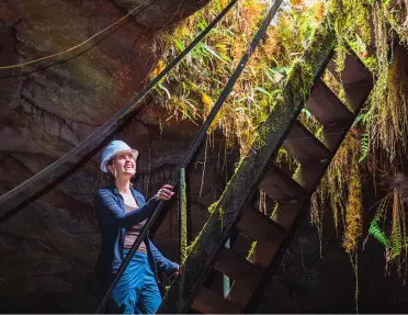 Woman wearing a hardhat, climbing a ladder in a cave