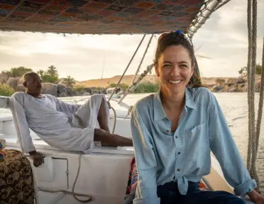 A woman enjoying a ride on a felucca, a traditional Egyptian wooden sailboat on the Nile River in Egypt.