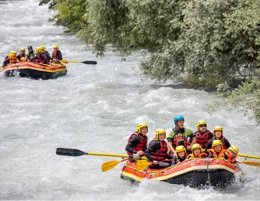 Two groups of people white water rafting in two separate boats