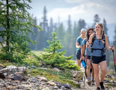 A group of women on a hike surrounded by forest trees and rocky terrain in Canada.