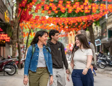 Two women and two men walking through a street with red decorations along the street
