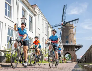Families biking on a stone road with a large windmill in the background