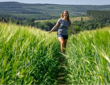 Woman walking through a tall field of weeds