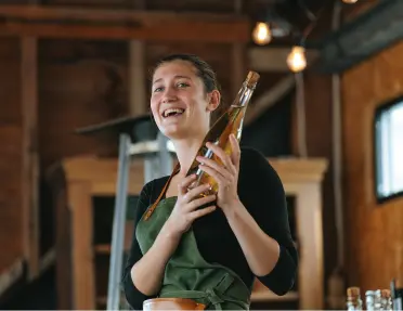 Woman wearing a green apron, holding a bottle of wine