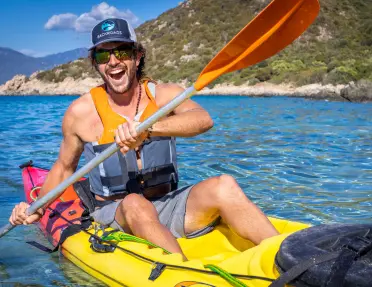 Man laughing while paddling on a yellow kayak
