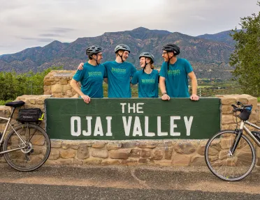 Four people standing behind a green Ojai Valley sign