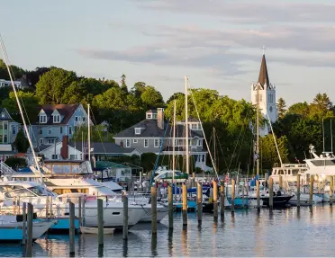 Boat port with large sail boats and houses in the back