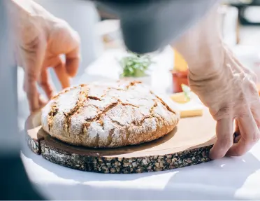 Plate with a loaf of bread and two hands grabbing the loaf