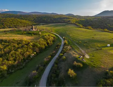 Long road surrounded by a grassy field and trees
