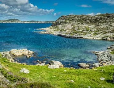 Coastal shore with a grassy hill and blue water