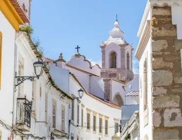 Alleyway of a town center with a large, white cathedral in the background