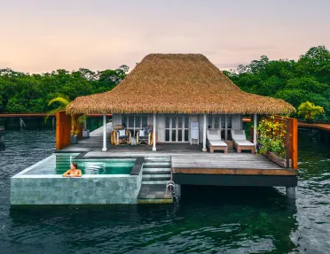 Woman sitting in an outdoor pool outside of a cottage