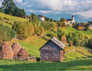 Cottage building in a large field with rolling hills and trees